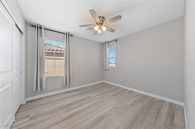 empty room featuring light wood-type flooring, baseboards, ceiling fan, and visible vents