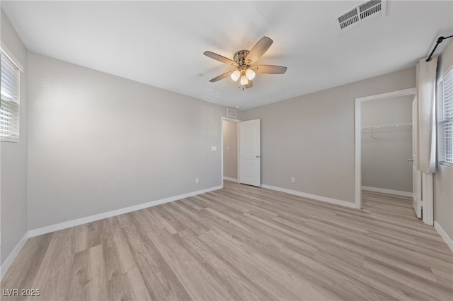 unfurnished bedroom with baseboards, visible vents, a walk in closet, and light wood-type flooring