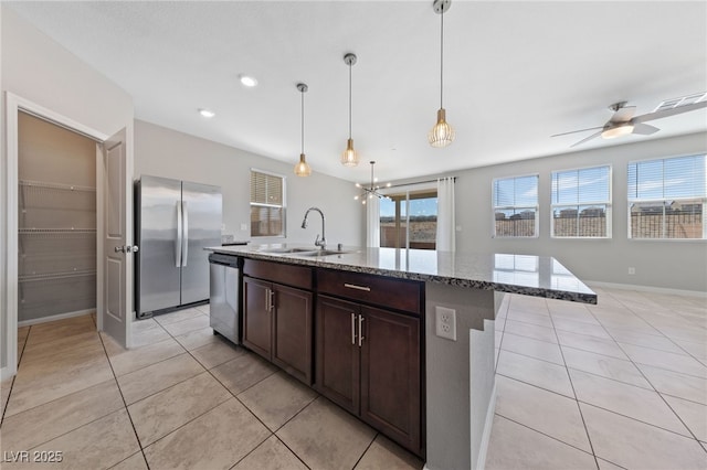 kitchen with light stone countertops, light tile patterned floors, appliances with stainless steel finishes, and a sink