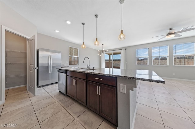 kitchen with dark brown cabinetry, light tile patterned flooring, light stone countertops, a sink, and appliances with stainless steel finishes