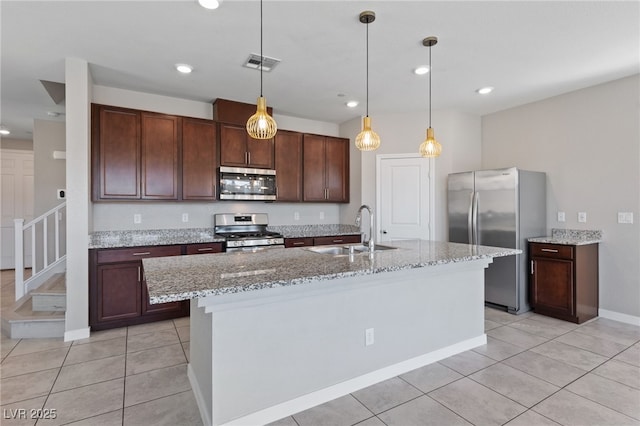 kitchen featuring light tile patterned flooring, stainless steel appliances, a sink, visible vents, and pendant lighting