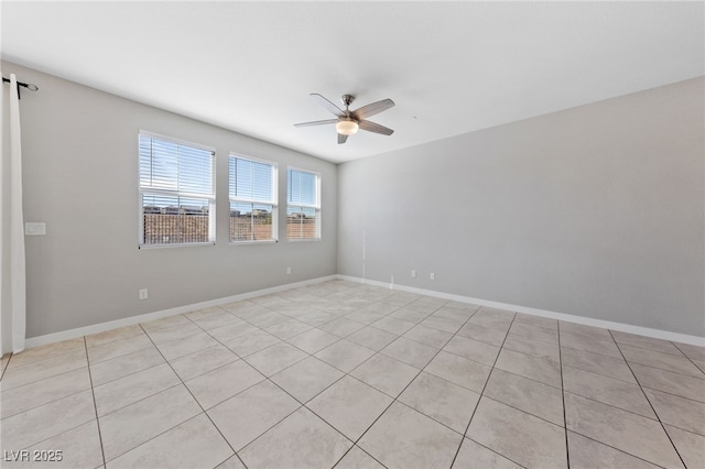 spare room featuring a ceiling fan, baseboards, and light tile patterned floors