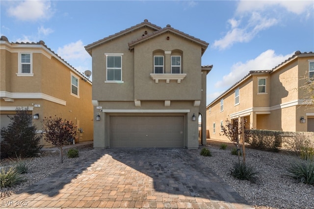 view of front of house featuring an attached garage, a tiled roof, decorative driveway, and stucco siding