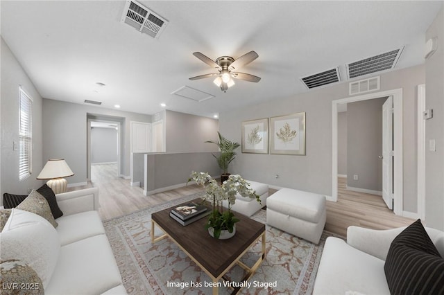 living area featuring light wood-style floors, attic access, and visible vents