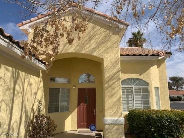 entrance to property featuring stucco siding and a tiled roof