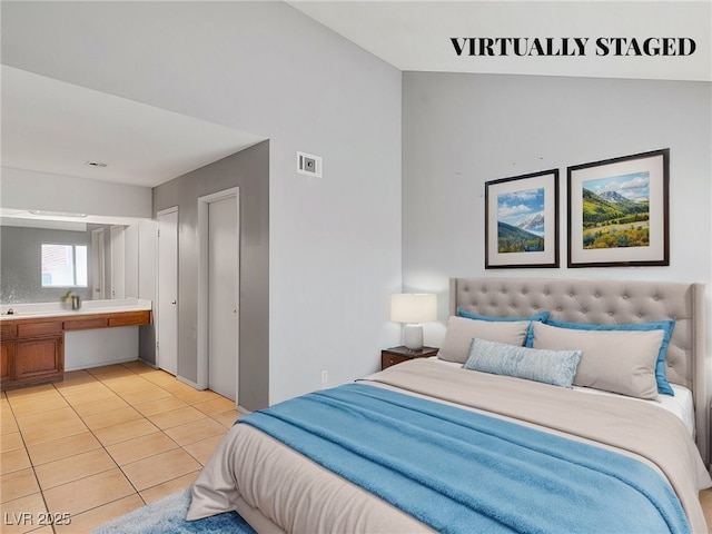 bedroom with light tile patterned floors, visible vents, and ensuite bathroom