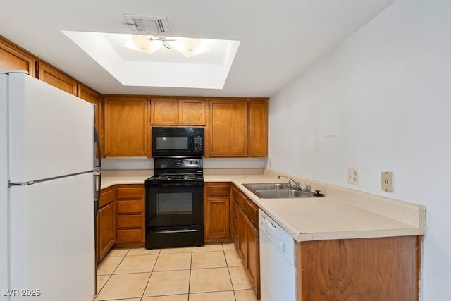 kitchen with black appliances, brown cabinetry, a sink, and visible vents