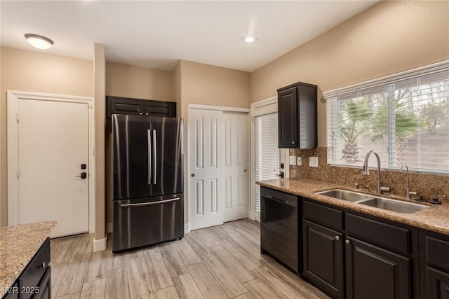 kitchen with light wood finished floors, tasteful backsplash, freestanding refrigerator, a sink, and dishwashing machine