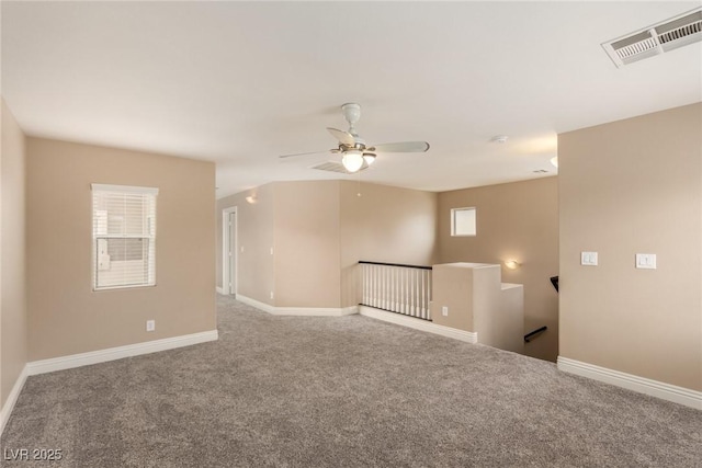 carpeted empty room featuring ceiling fan, visible vents, and baseboards