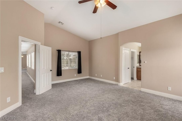 unfurnished bedroom with arched walkways, visible vents, light carpet, vaulted ceiling, and baseboards