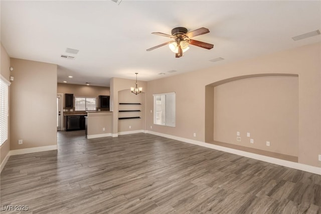 unfurnished living room featuring dark wood-style floors, visible vents, baseboards, and ceiling fan with notable chandelier