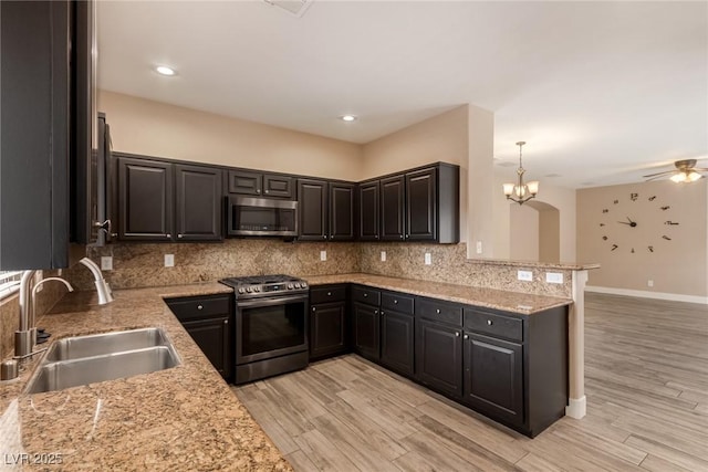 kitchen featuring backsplash, stainless steel appliances, a sink, and light wood finished floors