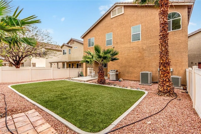 back of house featuring a patio, a yard, stucco siding, central AC, and a fenced backyard