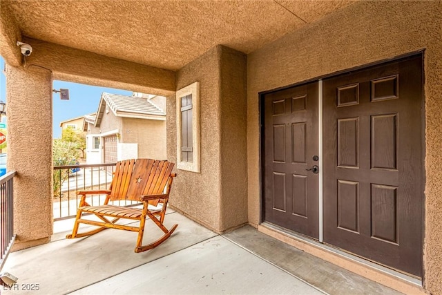 entrance to property featuring a balcony and stucco siding