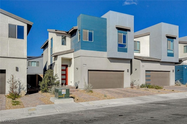 contemporary home with a garage, driveway, and stucco siding