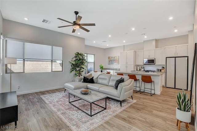 living area with visible vents, baseboards, light wood-style flooring, ceiling fan, and recessed lighting