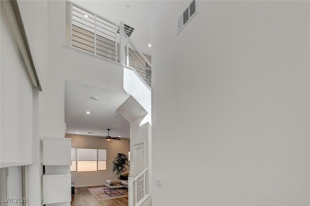 stairway featuring visible vents, ceiling fan, and wood finished floors