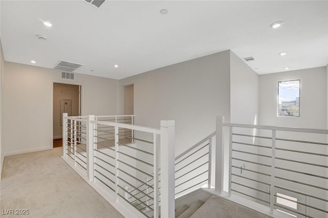 corridor featuring carpet floors, recessed lighting, visible vents, and an upstairs landing