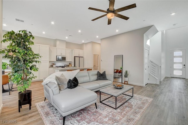 living room featuring light wood finished floors, visible vents, stairway, and recessed lighting