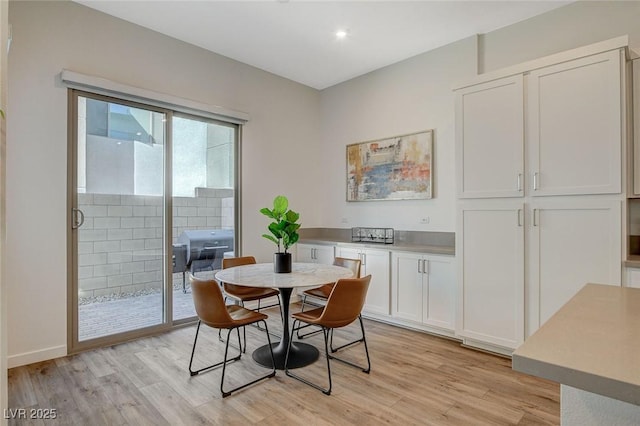 dining space featuring light wood-type flooring and baseboards