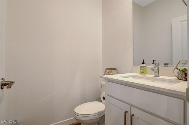 bathroom with baseboards, vanity, and toilet