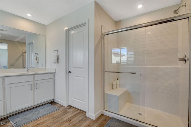 bathroom featuring a stall shower, baseboards, visible vents, wood finished floors, and vanity