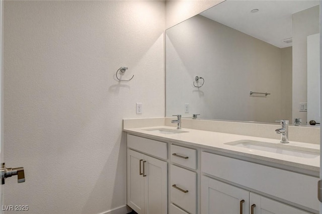 full bathroom featuring a sink, baseboards, and double vanity