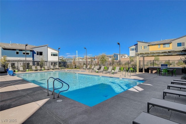 community pool with a patio area, fence, and a residential view