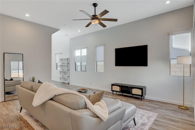 living room featuring light wood finished floors, a healthy amount of sunlight, and baseboards