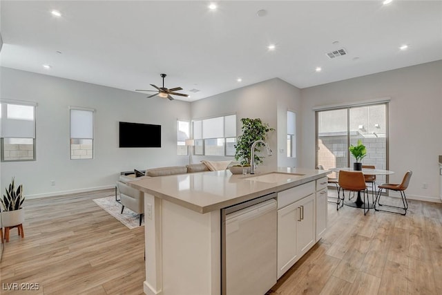 kitchen with a sink, a healthy amount of sunlight, light wood-type flooring, and dishwasher