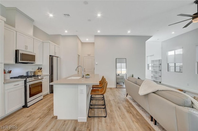 kitchen with visible vents, stainless steel appliances, a sink, and open floor plan