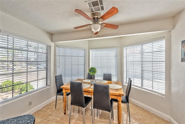 dining area with baseboards, a textured wall, visible vents, and a textured ceiling