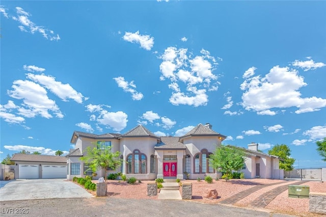 mediterranean / spanish house featuring stucco siding, driveway, a garage, and fence