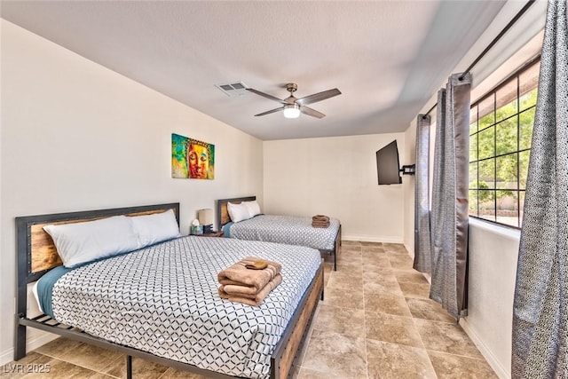 bedroom with visible vents, baseboards, a textured ceiling, and a ceiling fan