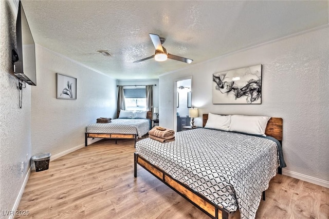 bedroom featuring light wood finished floors, crown molding, and a textured wall