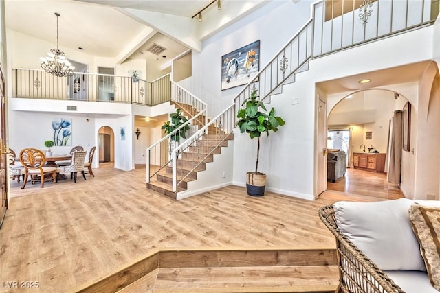 entrance foyer with stairway, wood finished floors, baseboards, an inviting chandelier, and arched walkways