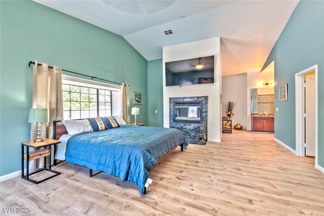 bedroom featuring a fireplace, wood finished floors, visible vents, and baseboards