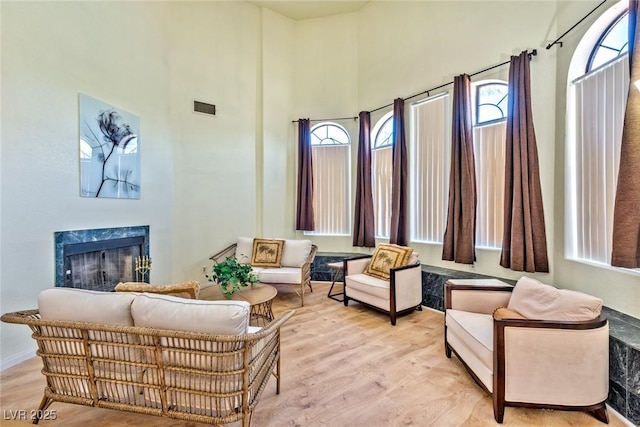 interior space with a high ceiling, light wood-style floors, visible vents, and a premium fireplace