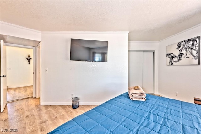 bedroom with a textured ceiling, crown molding, baseboards, and wood finished floors