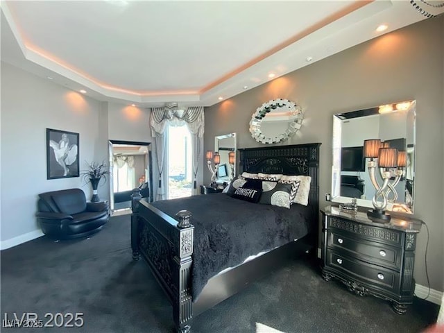 carpeted bedroom featuring a raised ceiling and baseboards