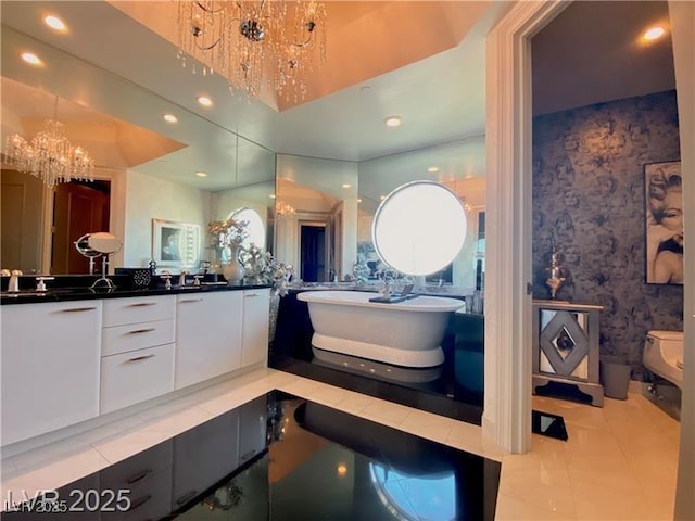 bathroom with toilet, recessed lighting, vanity, a freestanding bath, and an inviting chandelier