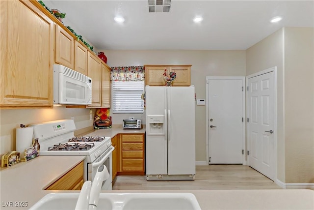 kitchen featuring white appliances, visible vents, light countertops, light brown cabinets, and recessed lighting