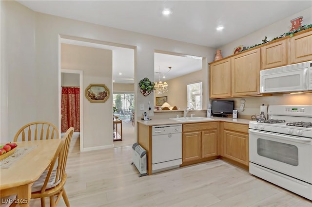 kitchen featuring white appliances, light countertops, a sink, and light brown cabinetry