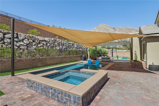 view of swimming pool featuring a fenced backyard, a mountain view, an in ground hot tub, a fenced in pool, and a patio area