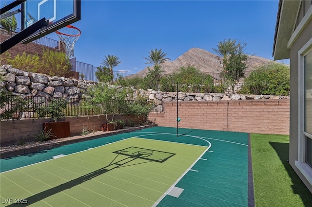 view of basketball court with basketball hoop, fence, and a mountain view