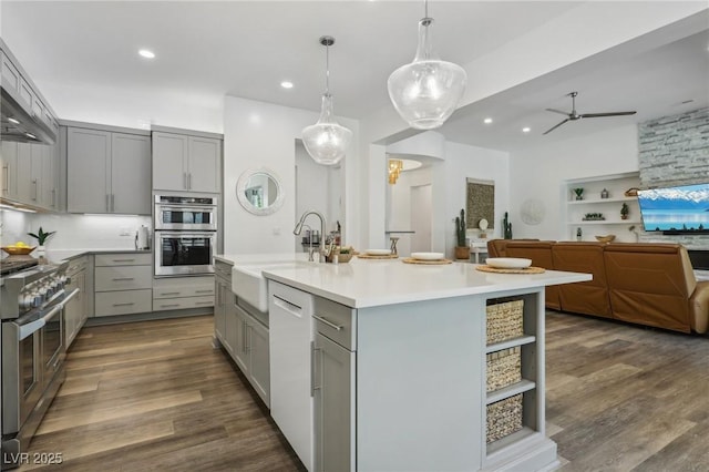 kitchen featuring light countertops, stainless steel appliances, gray cabinetry, open shelves, and a sink