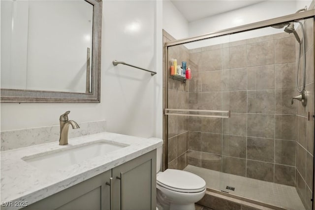 bathroom featuring vanity, a shower stall, and toilet