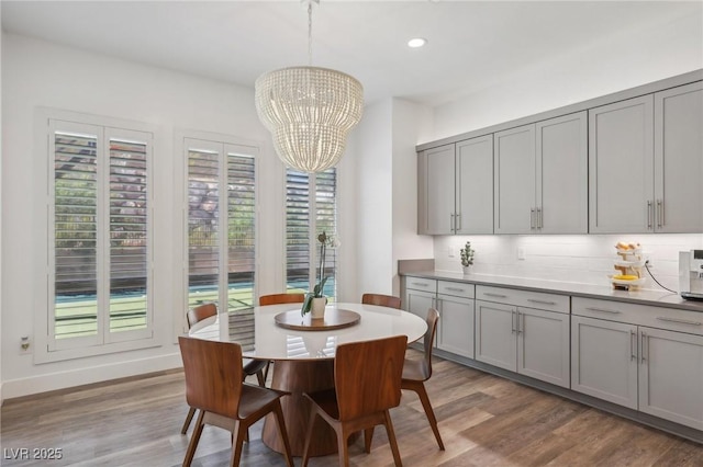 dining area with an inviting chandelier, baseboards, wood finished floors, and recessed lighting