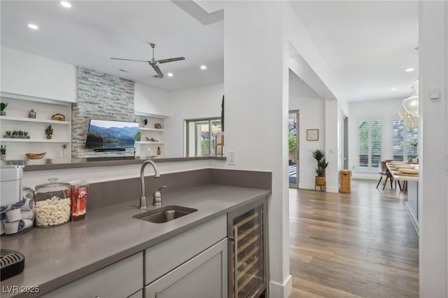 kitchen with wine cooler, a sink, recessed lighting, and wood finished floors