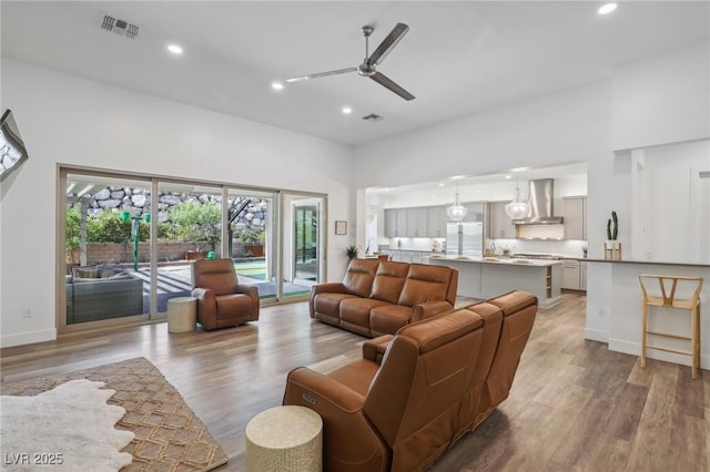 living area with visible vents, baseboards, ceiling fan, light wood-type flooring, and recessed lighting